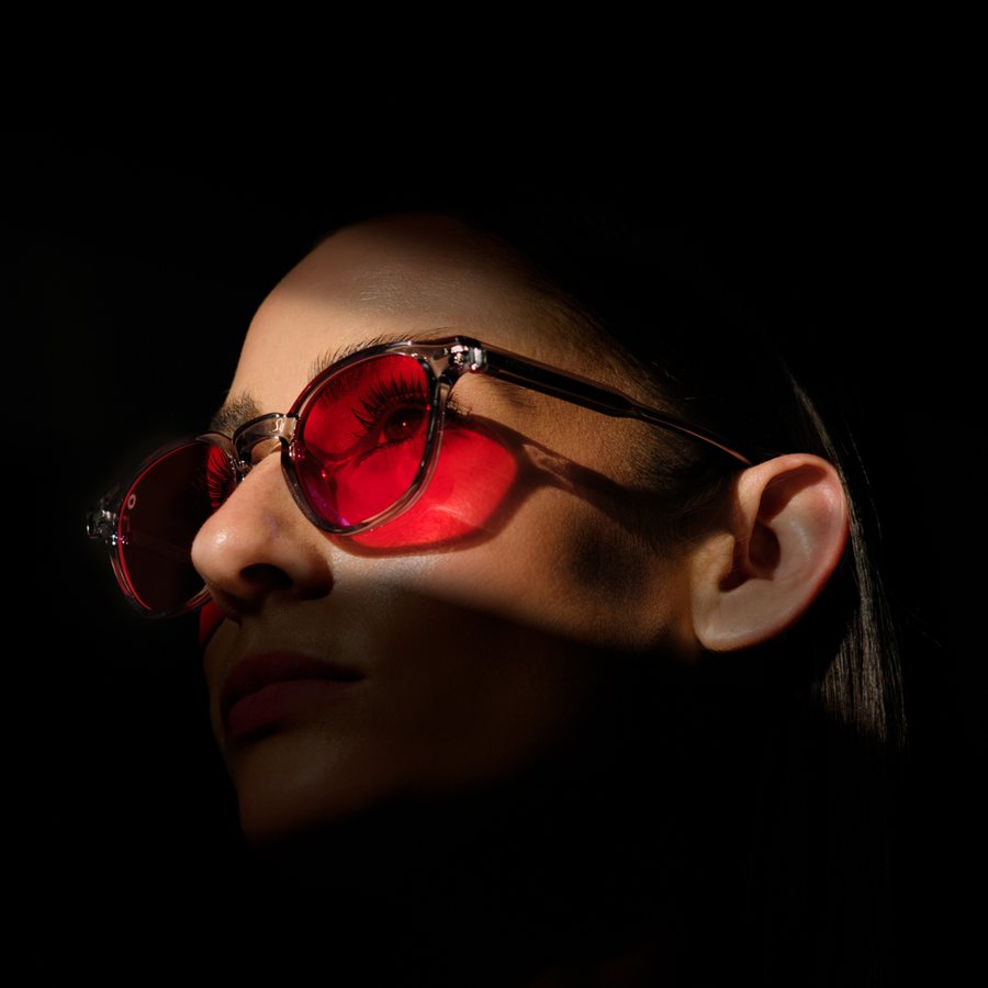 Woman in red lens glasses in low light